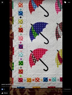 a quilted wall hanging with colorful umbrellas on it