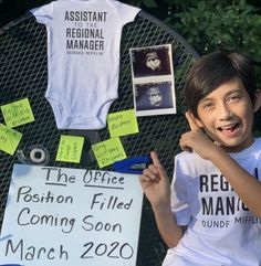 a young boy is holding up his shirt and posing for the camera with other signs