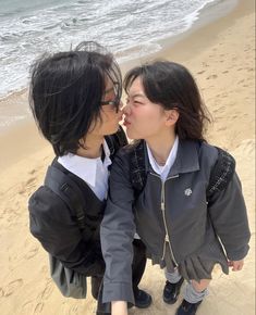 two women kissing each other on the beach