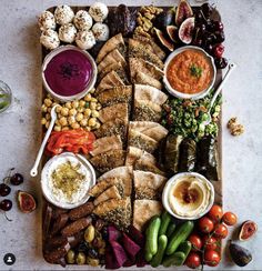 a platter filled with meats, vegetables and dips on top of a table