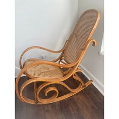 a wooden rocking chair sitting on top of a hard wood floor next to a wall