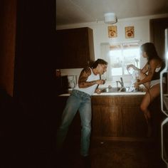 two people standing in a kitchen next to each other