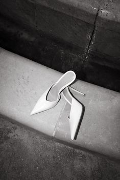 a pair of white shoes sitting on top of a cement bench next to a wall