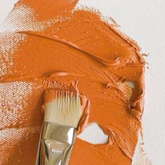 an orange paintbrush with some white paint on it