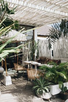 an outdoor patio with lots of plants and chairs