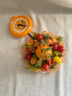 an orange clock sitting on top of a table next to fruits and vegetables in chains