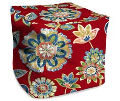 a red ottoman cover with blue and green flowers on the top, sitting in front of a white background