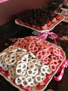 two trays filled with cookies and pretzels on top of a table