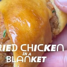 a hand is holding a sandwich with meat and cheese on it that says fried chicken in a blanket