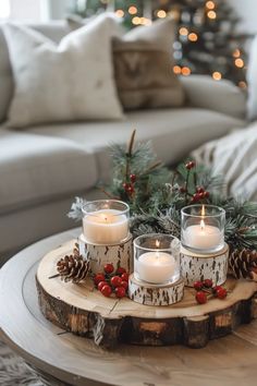 three candles are sitting on a wood slice with pine cones and berries around it in front of a christmas tree