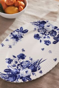 a blue and white plate sitting on top of a table next to a bowl of fruit