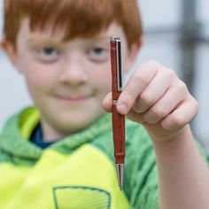 a young boy holding a pen in his right hand