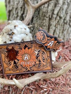 two leather wallets sitting on the ground next to a cotton ball and tree branch