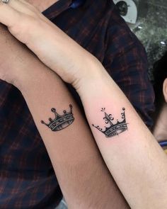 two people with matching tattoos on their arms, one has a crown and the other has a cross