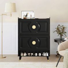 a black cabinet with gold knobs in a living room next to a chair and lamp