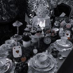 a table topped with lots of plates and cups filled with cake next to a clock