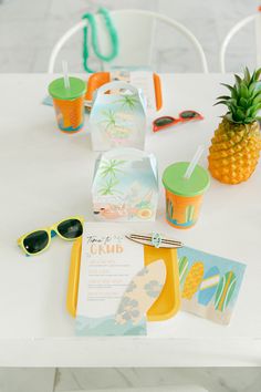 pineapples, sunglasses and other items are sitting on a white table with chairs