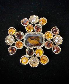 DESCRIPTION: What a pretty pin this is.  The pin is a stylized Maltese Cross. Smokey topaz, amber, & sable faceted, round-cut crystals are set into individual petal baskets. The pretty smokey topaz center crystal is rectangular & surrounded by a rope border. The bronze-tone metal and black enameling (Japanning) give the piece an antique look.  All the crystals are gold foiled & set open back. The reverse is texturized.  Enjoy! *  *  *   *DIMENSIONS: ~2-1/4" x 2" *Wt.: ~32 gms *HALLMARK(s): unsigned *CONDITION: good with all crystal present. Very little wear to the crystals & intact gold foil reverses. I see a little bit of old glue. Roll-over clasp holds tightly.  * * * Please dive into the photos for yourself. Keep in mind that unless stated, these are VINTAGE pieces.  Superficial wear sh Orange Brooch Jewelry For Party, Rope Border, Smokey Topaz, Pretty Pins, Maltese Cross, Amber Color, Vintage Costume Jewelry, Color Crystal, Black Enamel