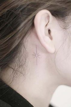 a woman's ear with a small star tattoo on it