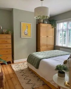 a bed room with a neatly made bed next to a dresser and window sill