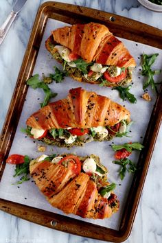 three sandwiches with meat and vegetables on a tray