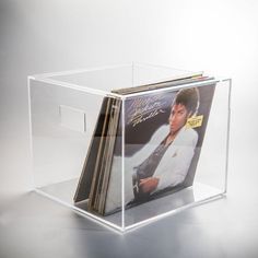 an acrylic display case with vinyl records in the front and back, on a grey background