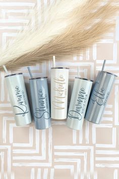 four personalized travel tumblers sitting next to a feather