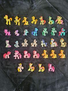 small pony figurines sitting on top of a black blanket