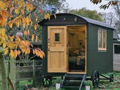 a small wooden cabin sitting on top of a lush green field next to a tree