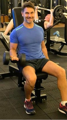 a man is sitting on a bench with two dumbbells