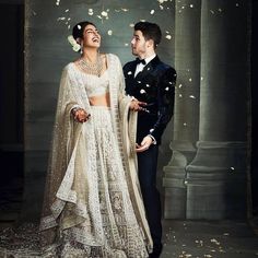 a man and woman standing next to each other in front of a white rose petals