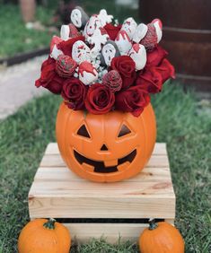 a pumpkin with roses and stuffed animals in it sitting on a wooden stand next to two orange pumpkins