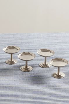 three silver plates sitting on top of a blue and white striped table cloth next to each other