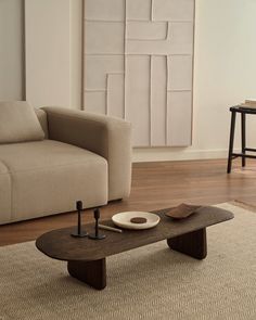 a living room with a couch, coffee table and chair in front of a painting