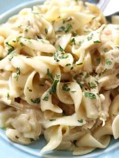 a blue plate topped with pasta covered in sauce and garnished with parsley