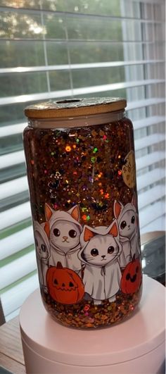 a glass jar with cats and pumpkins painted on it