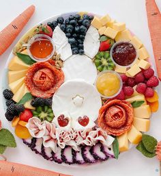 a platter with fruits, vegetables and cheeses on it is arranged in the shape of a rabbit