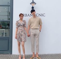 a man and woman standing next to each other in front of a sign that reads urbanic