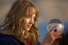 a woman holding a crystal ball in her hand and looking at it while standing next to another person