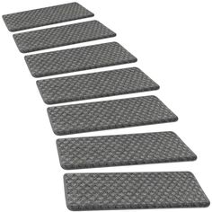 four gray mats are lined up in a row on a white background with no one is shown