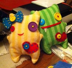 two stuffed animals sitting next to each other on a wooden table with various items around them