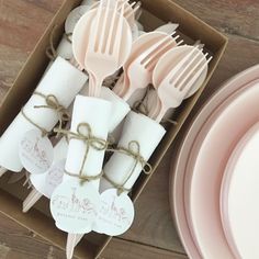 a box filled with pink plastic utensils and paper napkins on top of a wooden table