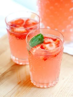 two glasses filled with watermelon and mint on top of a wooden cutting board