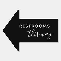 a black arrow with the words restrooms this way on it and an arrow pointing in opposite directions