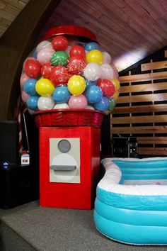 an inflatable ball machine next to a pool filled with balloons