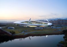 an aerial view of a futuristic building near a body of water