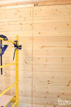 a yellow scaffold with tools on it in front of a wood paneled wall