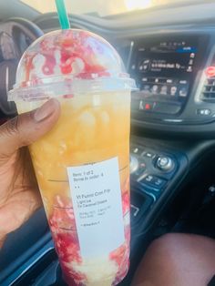 a person holding up a drink in their hand while sitting in the driver's seat of a car