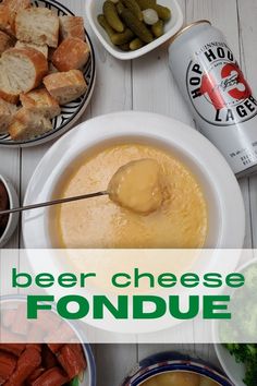 a table topped with bowls and plates filled with food next to bottles of beer, bread, and pickles