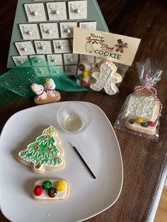 a white plate topped with cookies next to a small christmas tree and other decorations on top of a wooden table